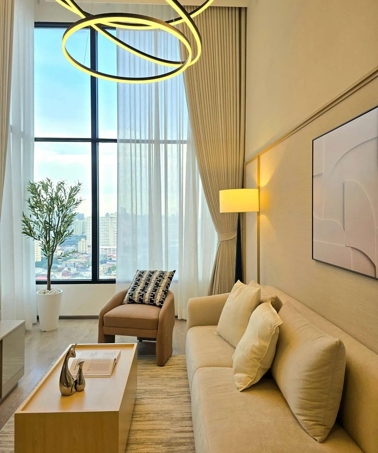 Living room with tall windows, linen curtains, a cream sofa and a gold ring pendant light